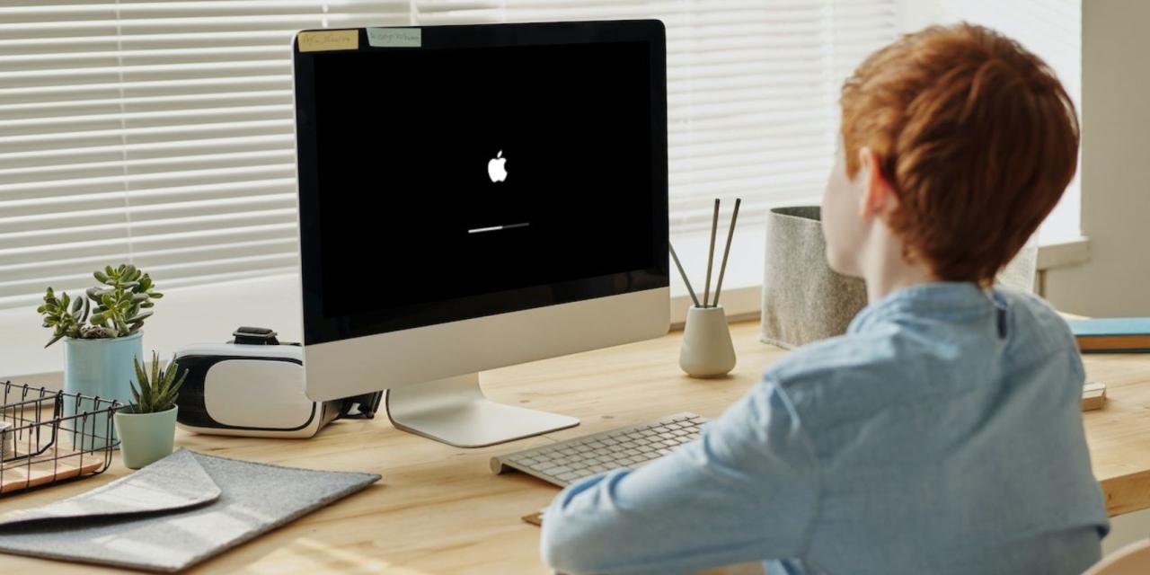 Boy watching Apple loading screen on an iMac