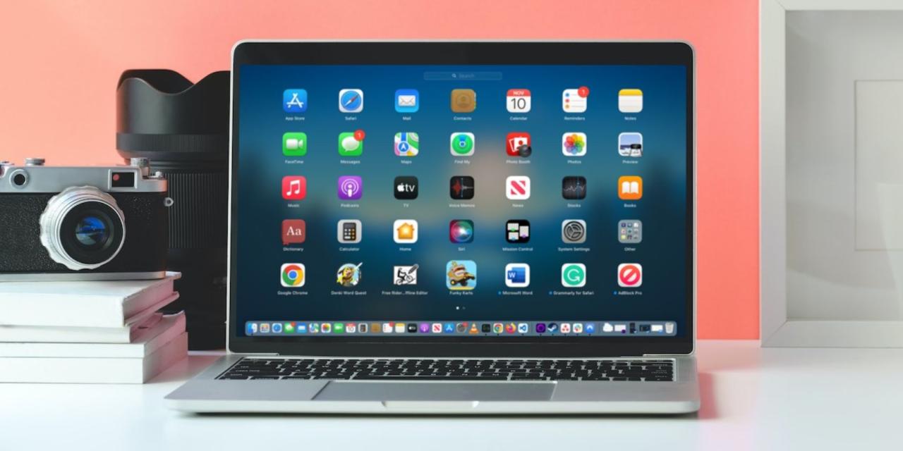 MacBook displaying launchpad on a table next to a camera