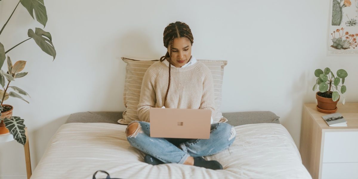 A lady using her Windows PC while sitting on bed