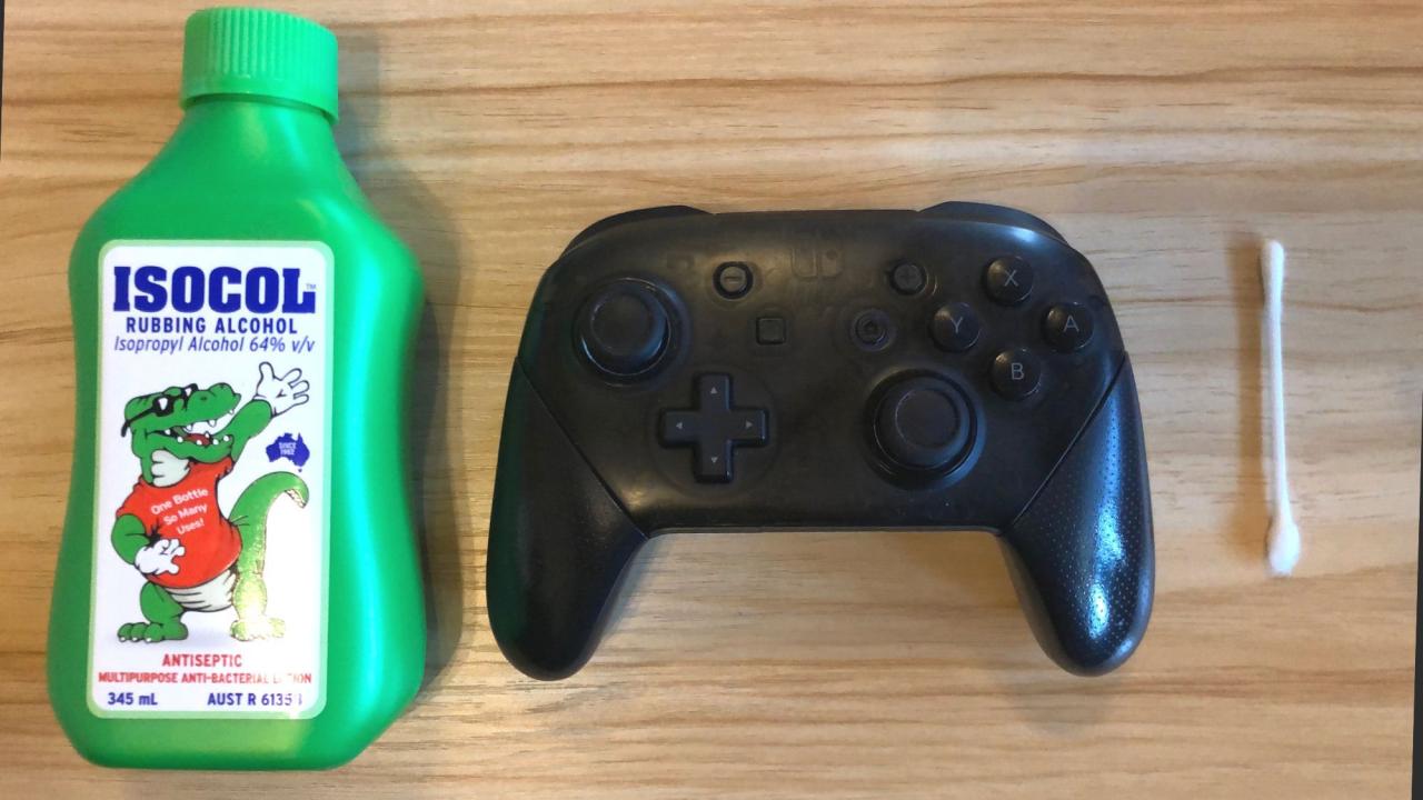 Rubbing alcohol and Q tip next to a Nintendo Switch Pro Controller