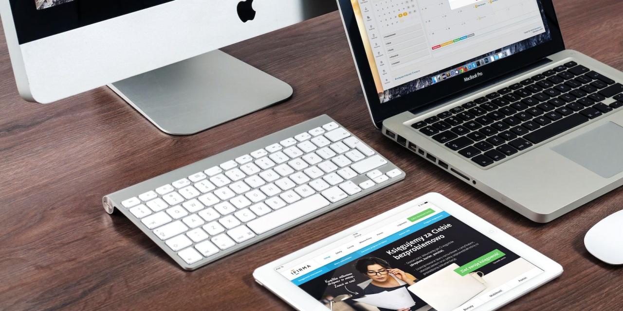 iMac with keyboard, MacBook, and iPad on a desk