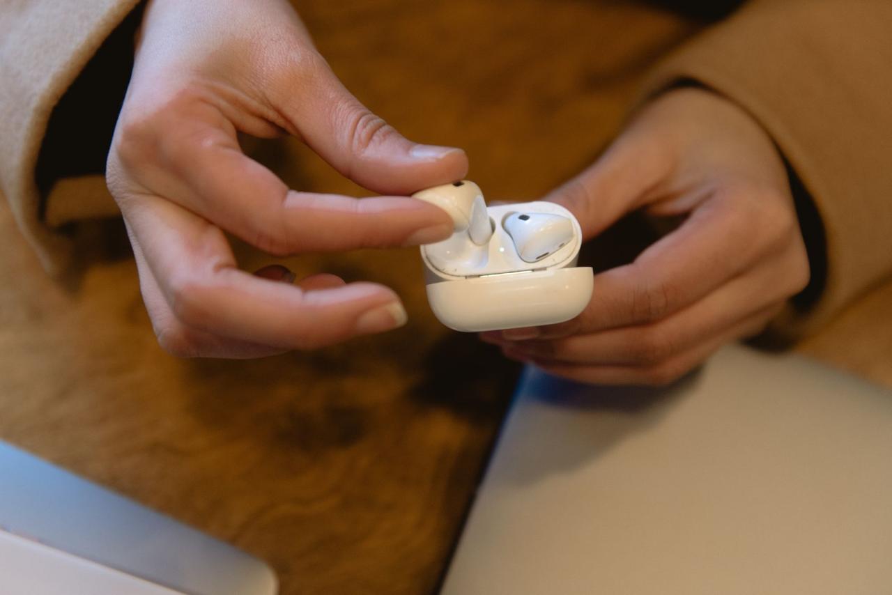 Hands holding a pair of wireless earbuds