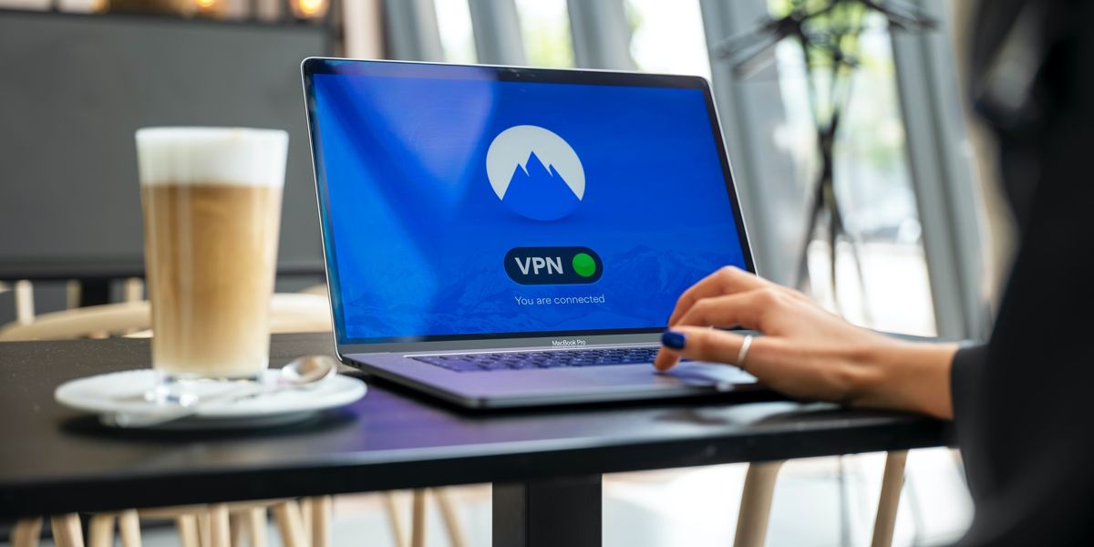 Someone typing on a laptop sitting on a coffee table. The laptop is connecting to a VPN.