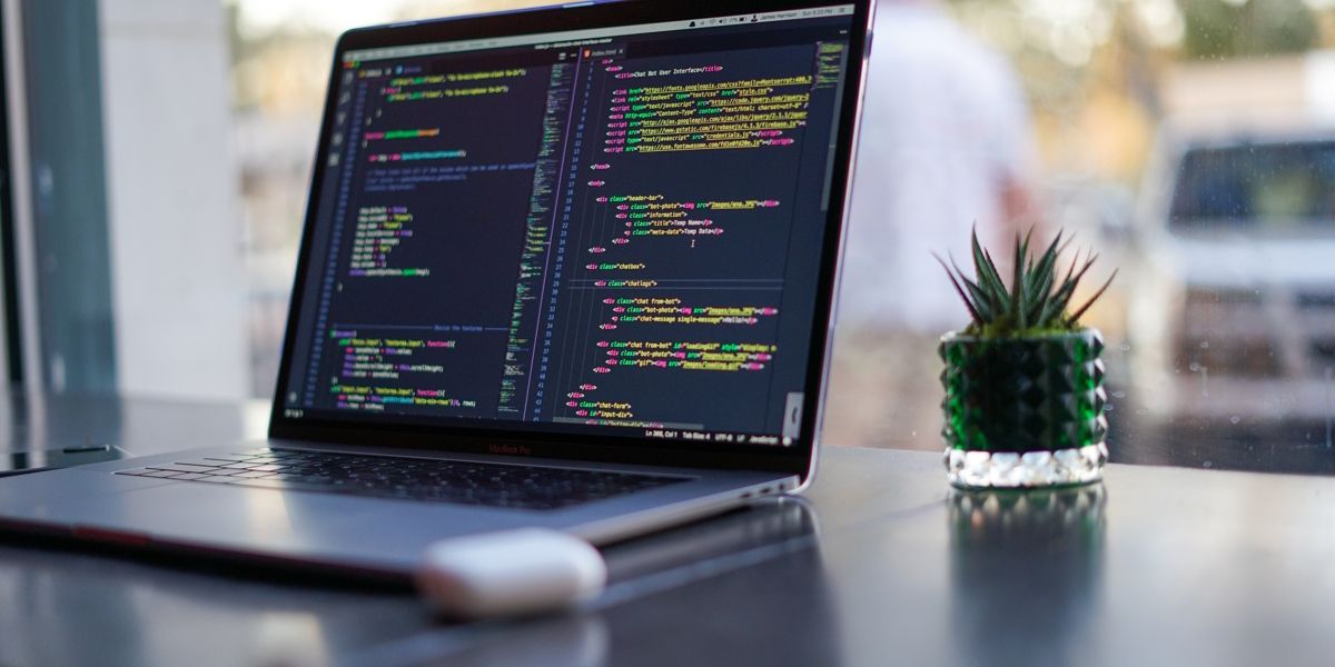 A laptop sitting on a desk with code open on the screen.