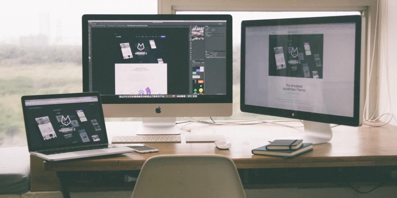 MacBook connected to two monitors on a desk