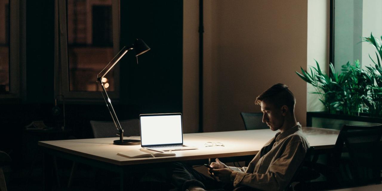 Reading lamp towering over a white-screen MacBook on a table