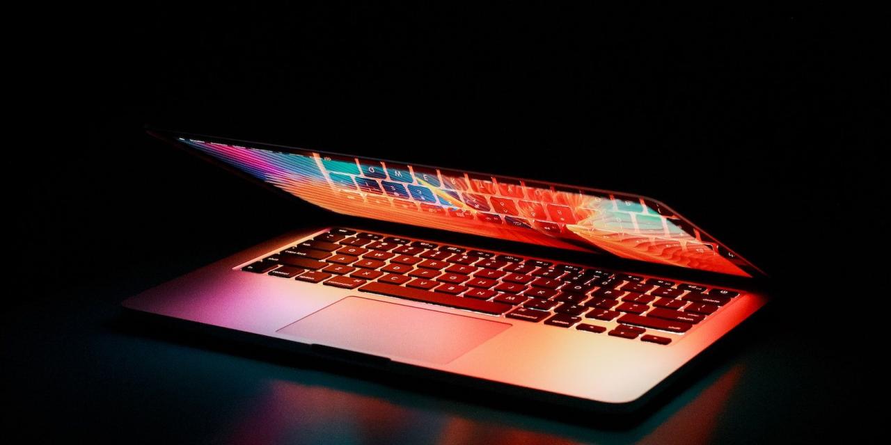 MacBook in a dark room with glowing keys and screen